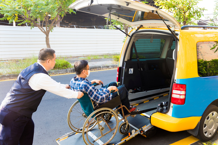 車いすの男性をタクシーに乗せている画像
